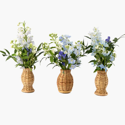 Three wicker vases with artificial flowers on a white background